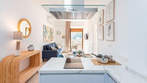 A modern kitchen with a marble countertop, a glass range hood, and a dining area with a blue sofa and a coffee table.