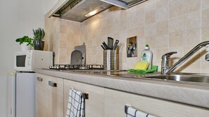 A kitchen with a microwave, stove, sink, and various utensils. - Bilocale Torre delle Ore (Lucca)
