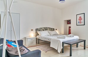 Un dormitorio con cama, mesita de noche y una pequeña mesa.