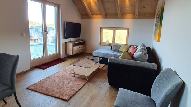 A modern living room with a high ceiling, a flat-screen TV, a sofa, and a coffee table.
