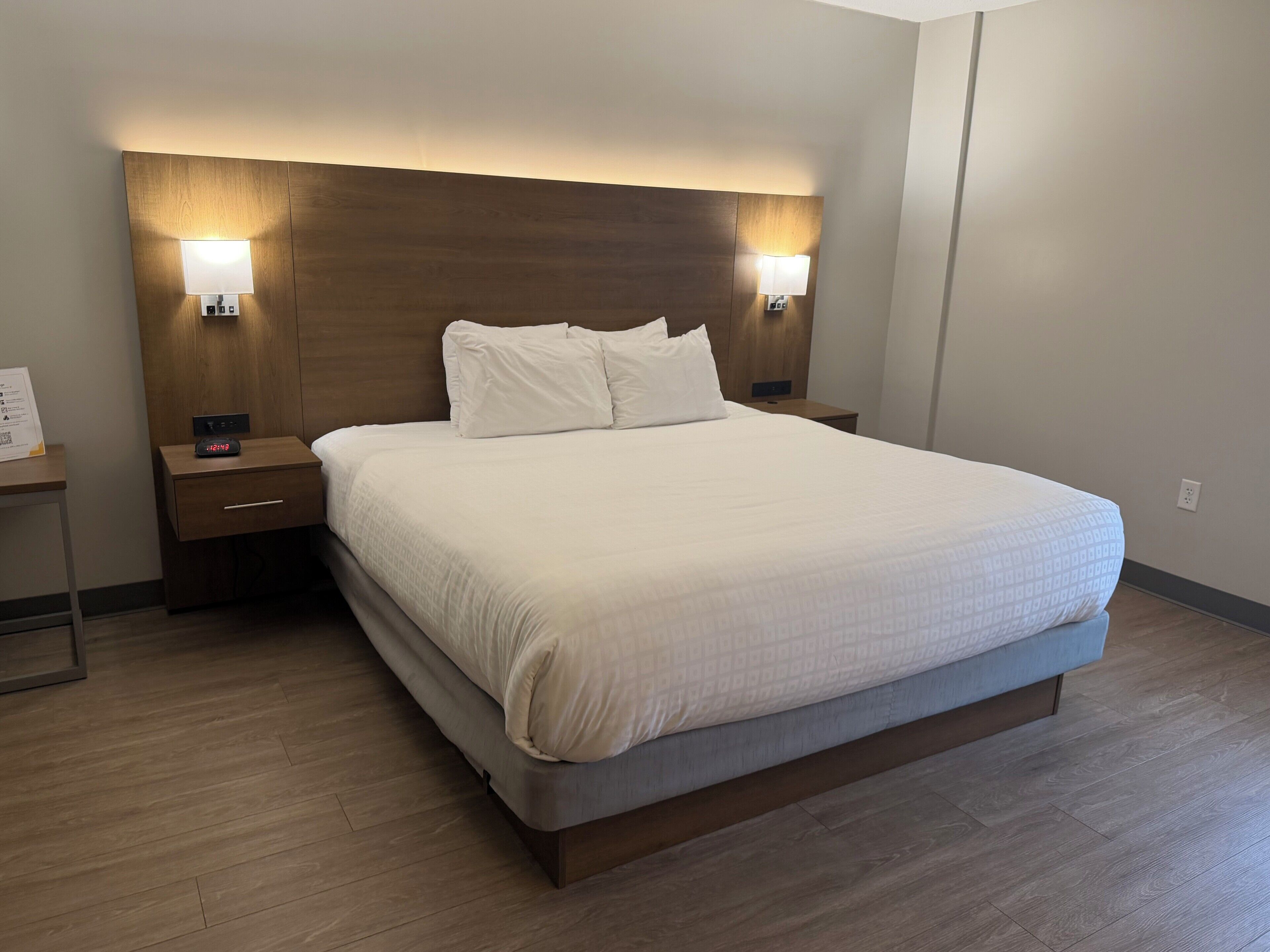 Een hotelkamer met een groot bed, twee nachtkastjes, een wandlamp en lampjes aan de muur.