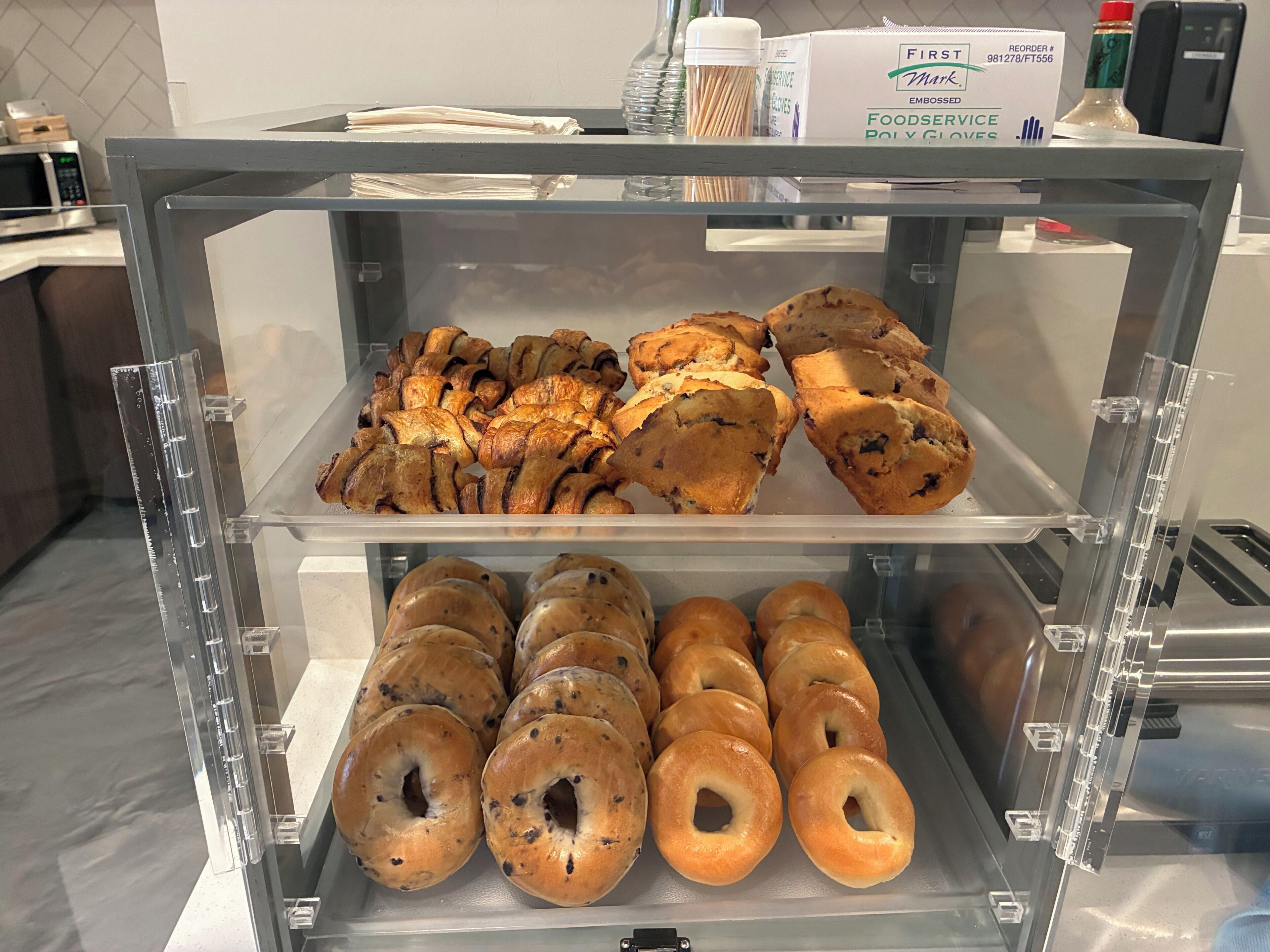 A bakery display case with pastries and bagels.