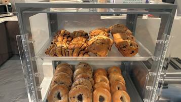 A bakery display case with pastries and bagels.