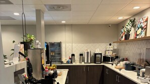 Una cocina moderna con piso de mármol, electrodomésticos de acero inoxidable y un espacio para café.