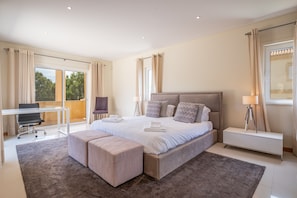 A modern bedroom with a large bed, a desk, and a bench. - VILLA SIBLING 2. Golf resort villa with 4 bedrooms and private pool,  (Quarteira)