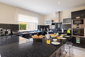 A modern kitchen with a granite countertop, stainless steel appliances, and a breakfast setup. - VILLA SIBLING 2. Golf resort villa with 4 bedrooms and private pool,  (Quarteira)