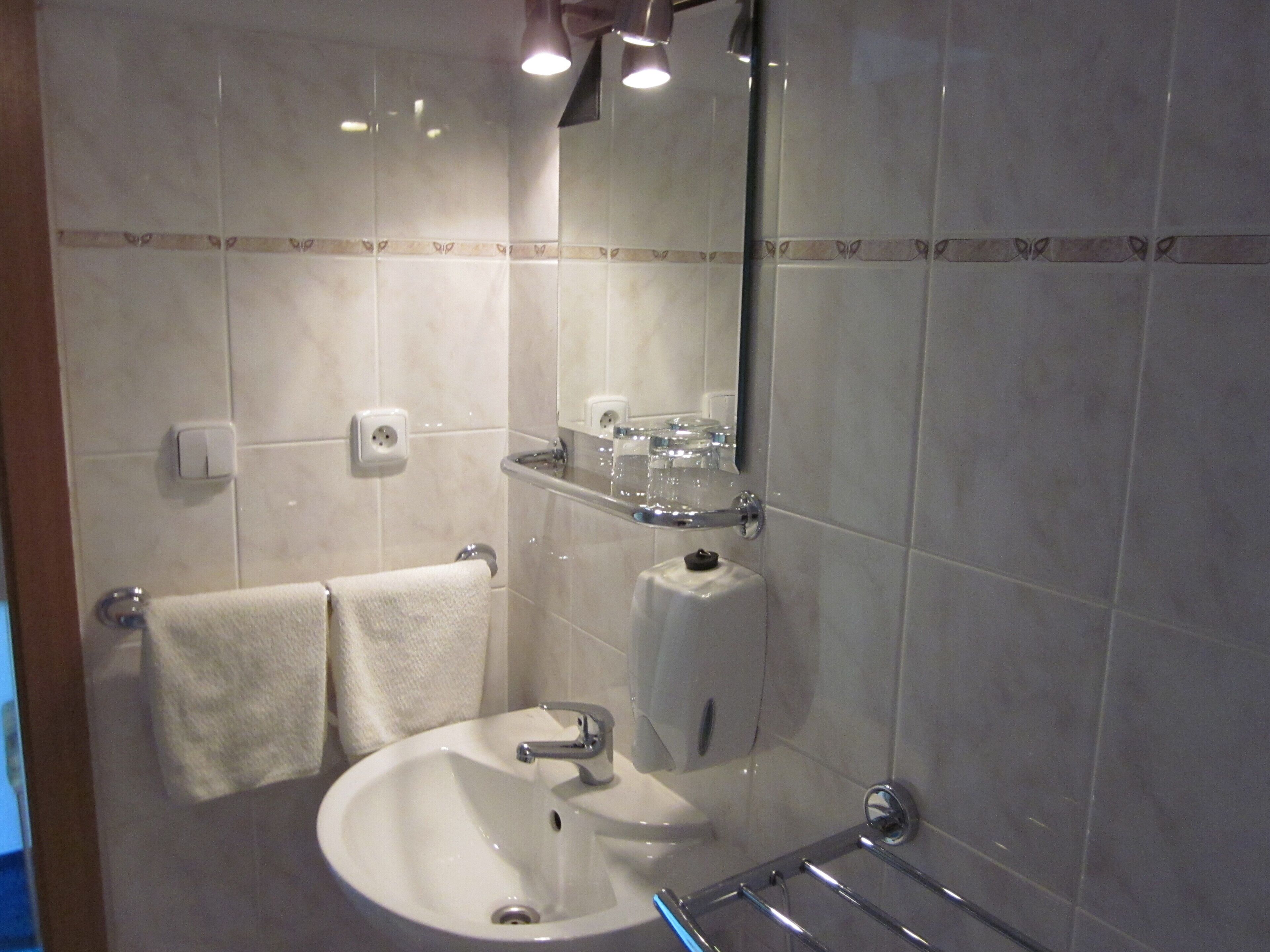 A bathroom with a sink, mirror, towel rack, and a glass shower enclosure.