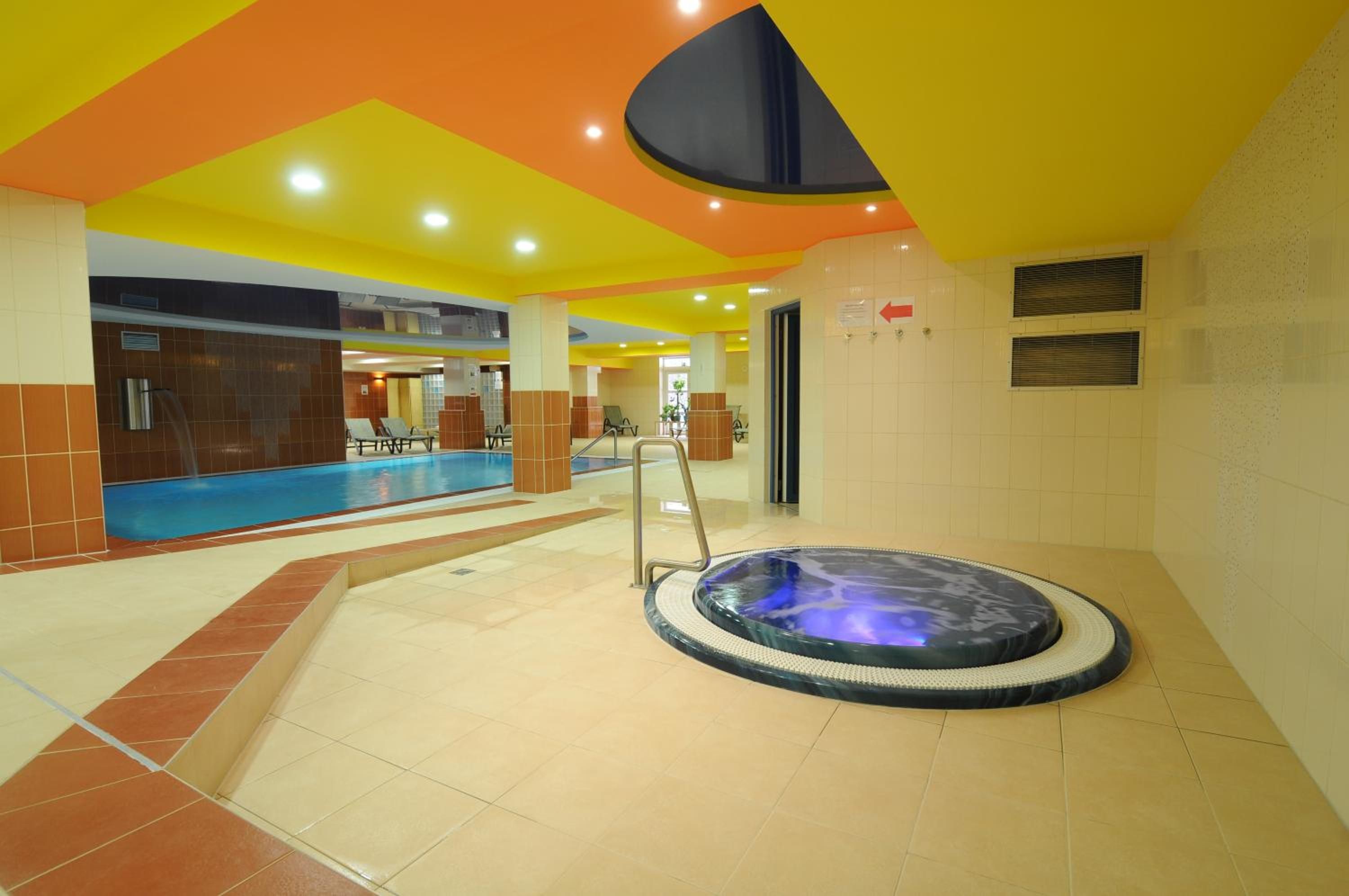 Ein Poolbereich mit Whirlpool, gefliesten Wänden und einer Decke mit geometrischem Muster.