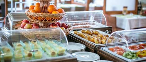 Buffet com diversas opções de comida, incluindo frutas, doces e saladas.