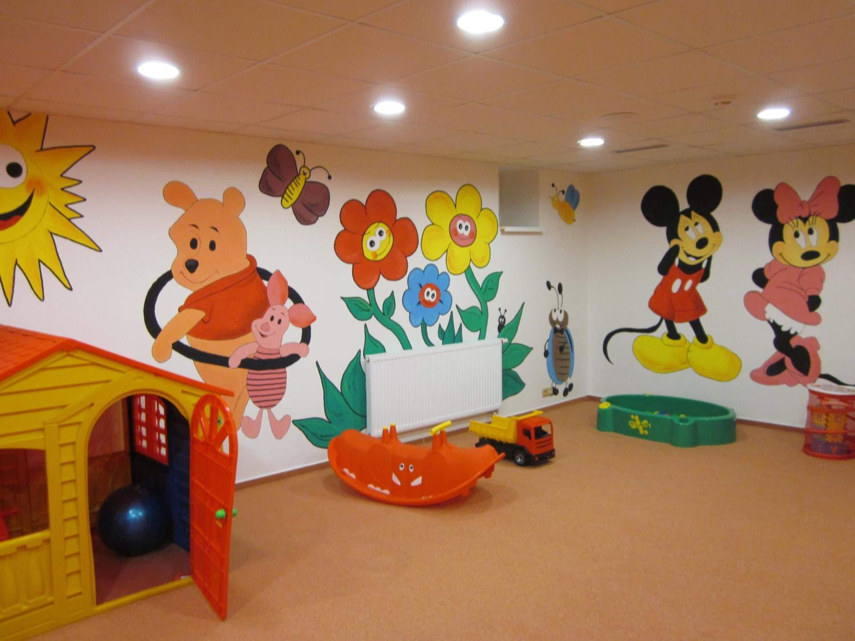 A children's playroom with cartoon murals, a playhouse, and various toys.