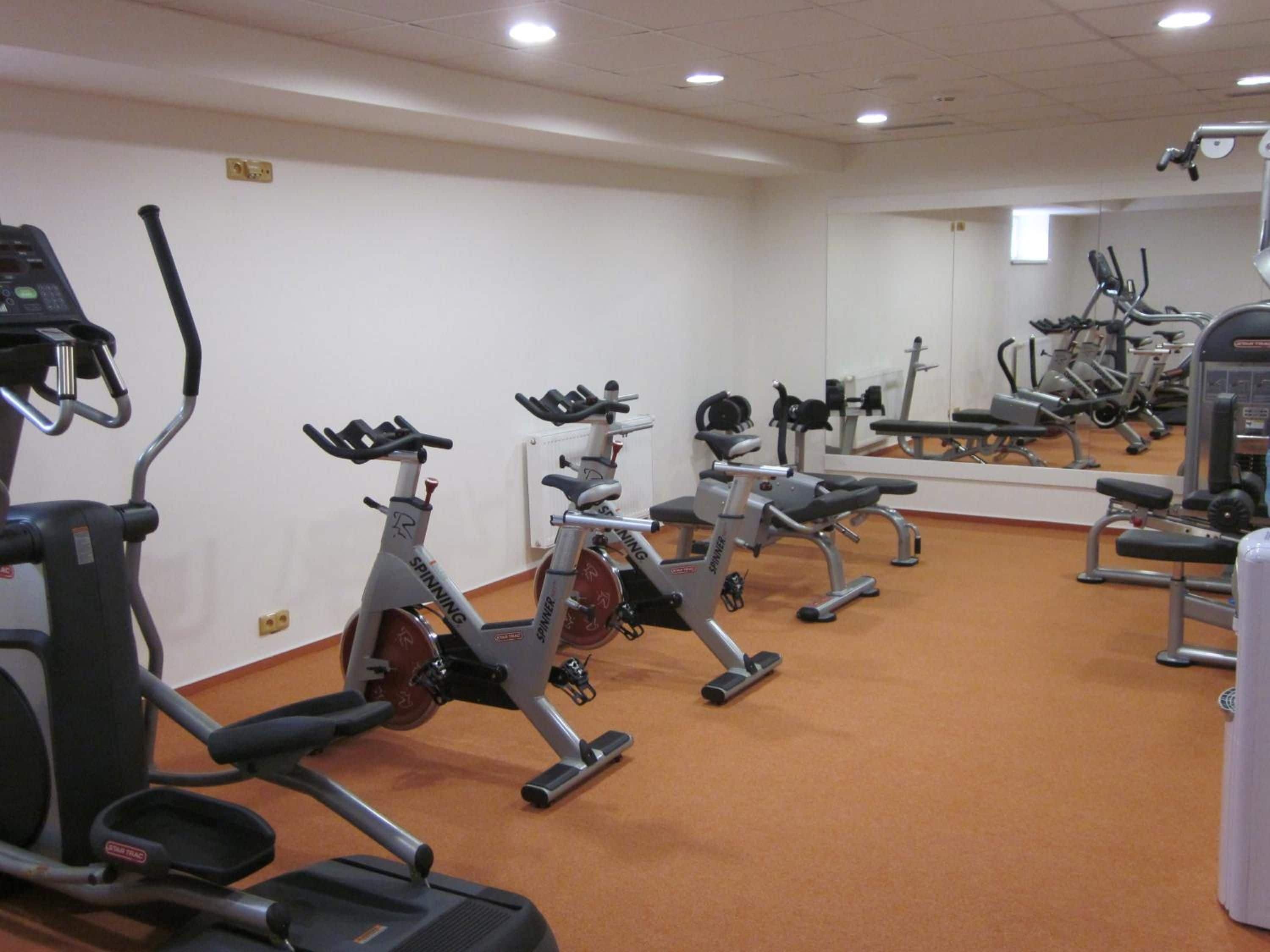 A gym with various exercise equipment including treadmills, stationary bikes, and weight machines.