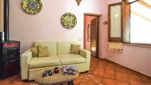 A living room with a sofa, a small table with remotes and a book, and two decorative plates on the wall. - Cozy home in Makari-S. Vito Lo Capo (Makari-S. Vito Lo Capo)