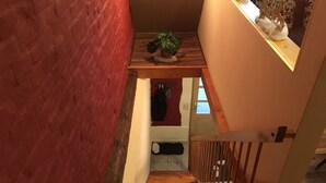 Una escalera de madera que lleva a una plataforma con una planta en maceta.