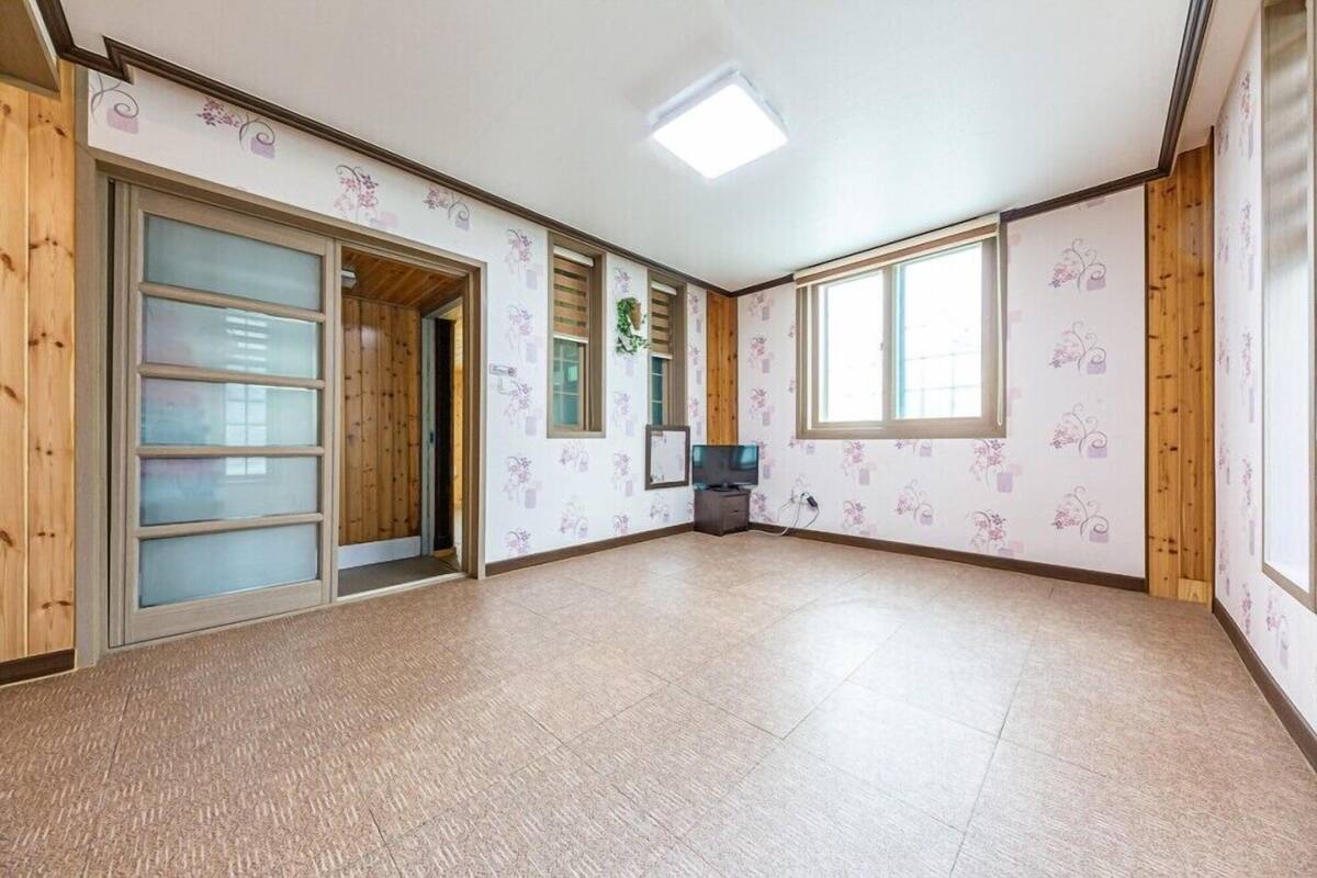 A spacious room with wooden walls, large windows, and a tiled floor.