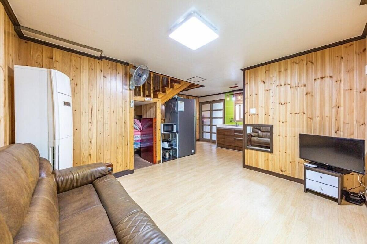 A spacious living room with a brown leather sofa, a flat-screen TV, and a wooden interior.