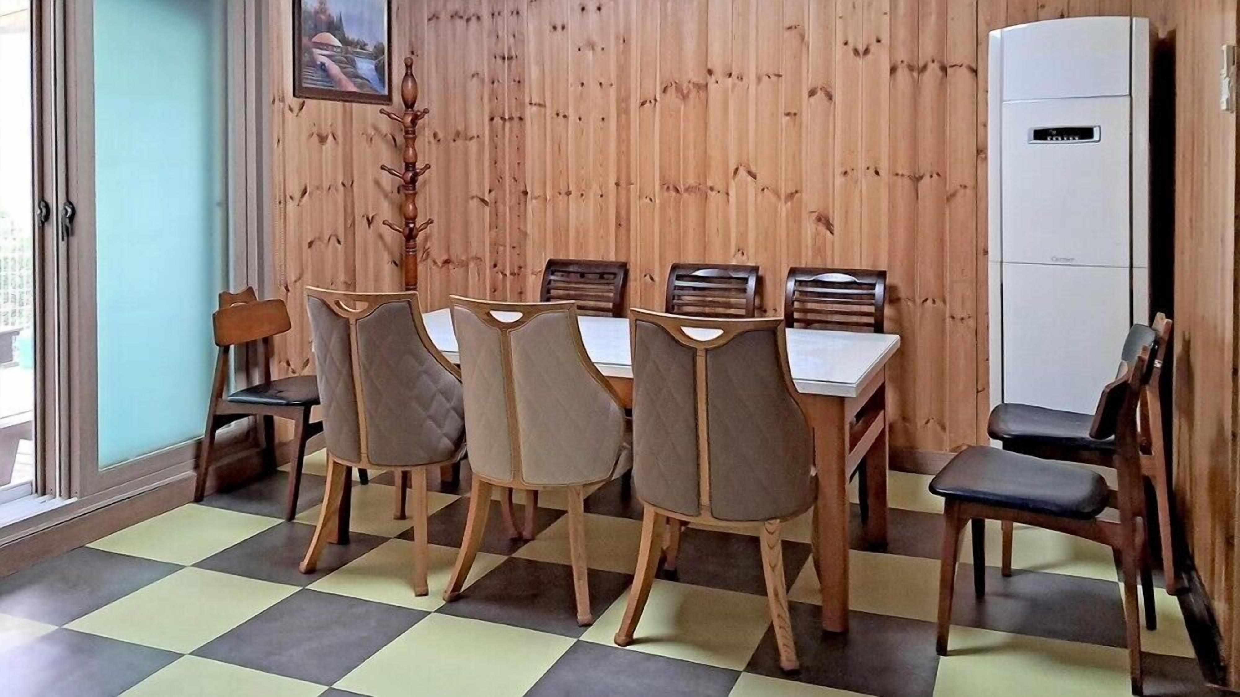 A dining area with a wooden paneled wall, a white refrigerator, and a checkered floor.