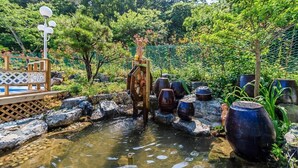 Un jardin paisible avec un petit étang, un pont en bois et des lanternes de style japonais traditionnel.