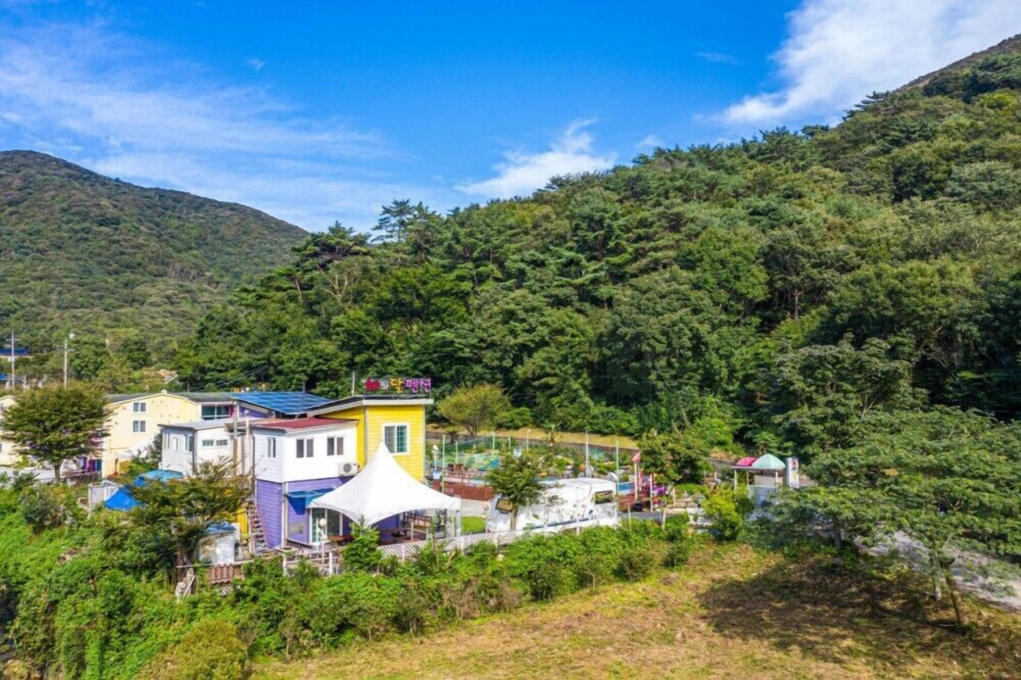 A residential area with houses, a white tent, and a mountain backdrop.