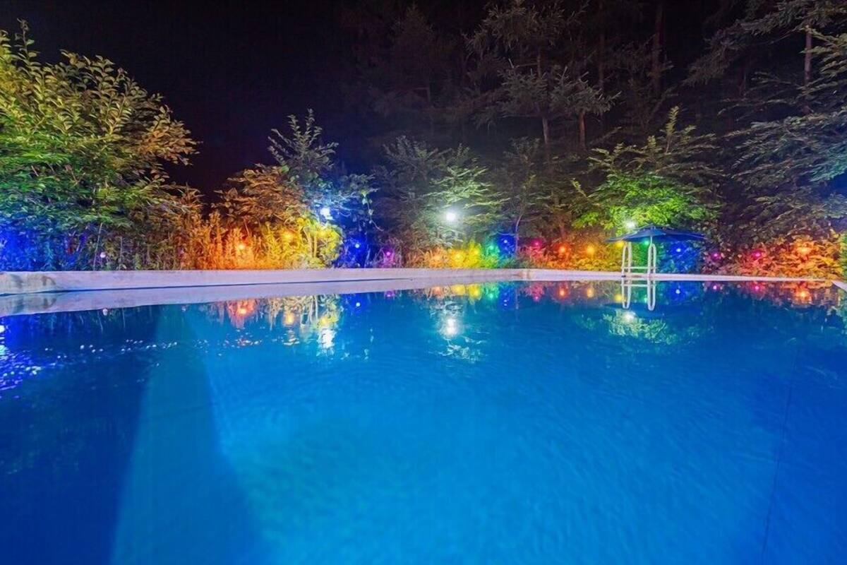 A nighttime swimming pool with colorful lights reflecting on the water.