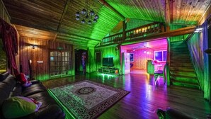 A spacious living room with a wooden ceiling, a large TV, and a plush sofa. - Sunny Hill Pension (Gapyeong)