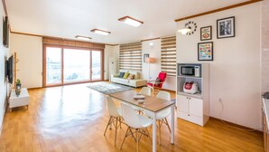 Una sala de estar moderna con comedor, ventanas amplias y una cocina con microondas y tostadora.