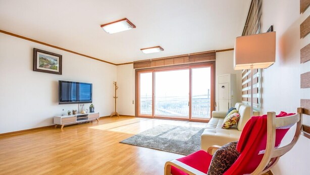 Un salón amplio con un ventanal grande, un televisor de pantalla plana, un sofá y una silla roja.