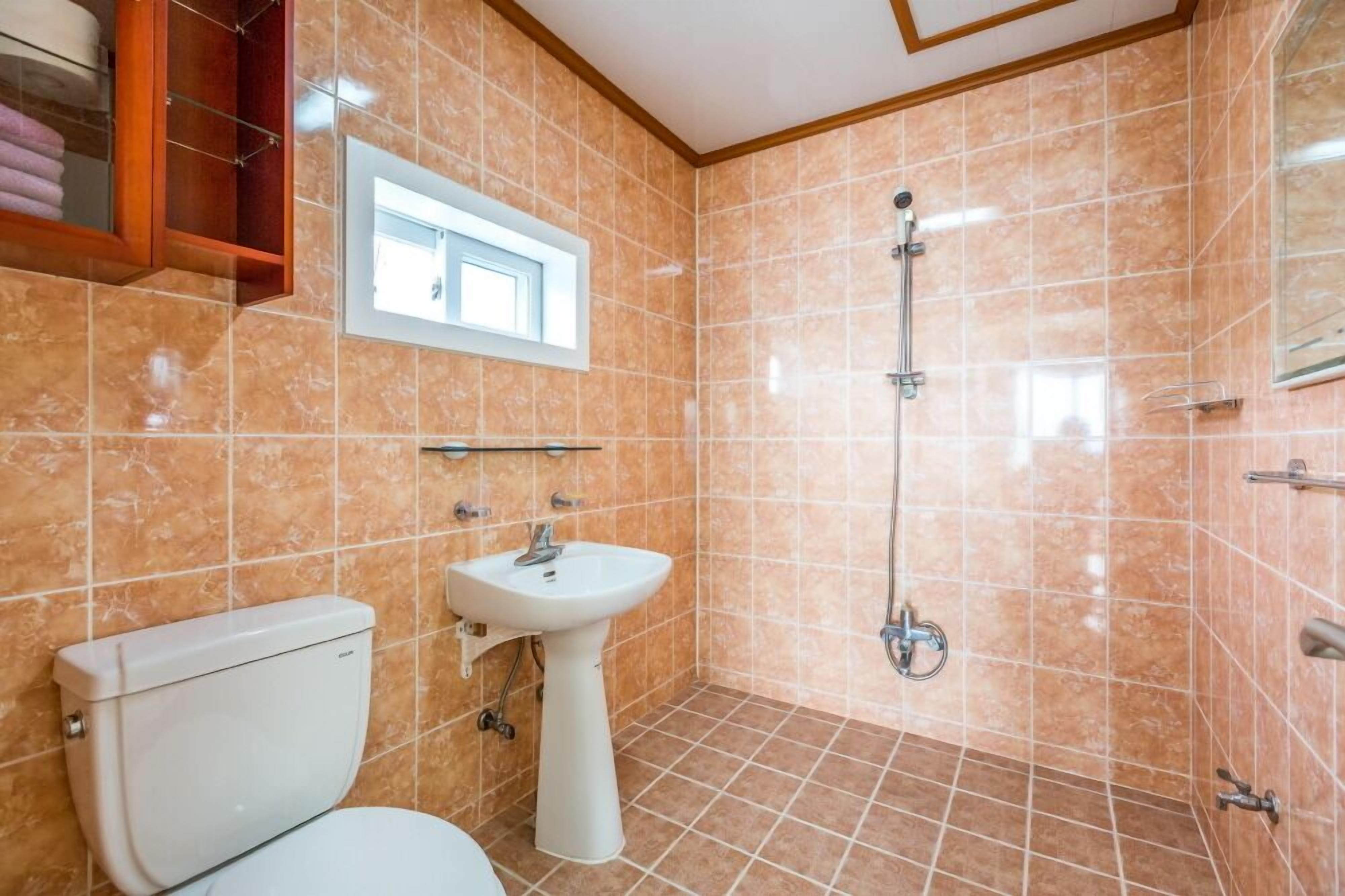 A bathroom with a toilet, sink, and shower.