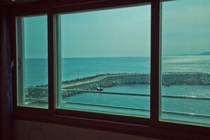 Vista a través de una ventana de una zona costera con un muelle y una masa de agua.