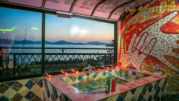A room with a view of a body of water, a tiled floor, and a mosaic wall.