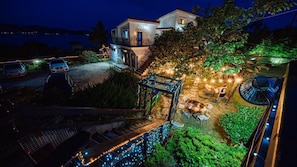 A residential property with a well-lit patio, a covered outdoor seating area, and a view of a body of water. - Santamonica Pension (Geoje)