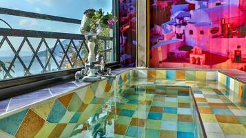 A tiled pool area with a view of the sea and a colorful mural.