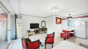 Habitación con mesa de comedor, sillas, televisor, espejo y kitchenette.