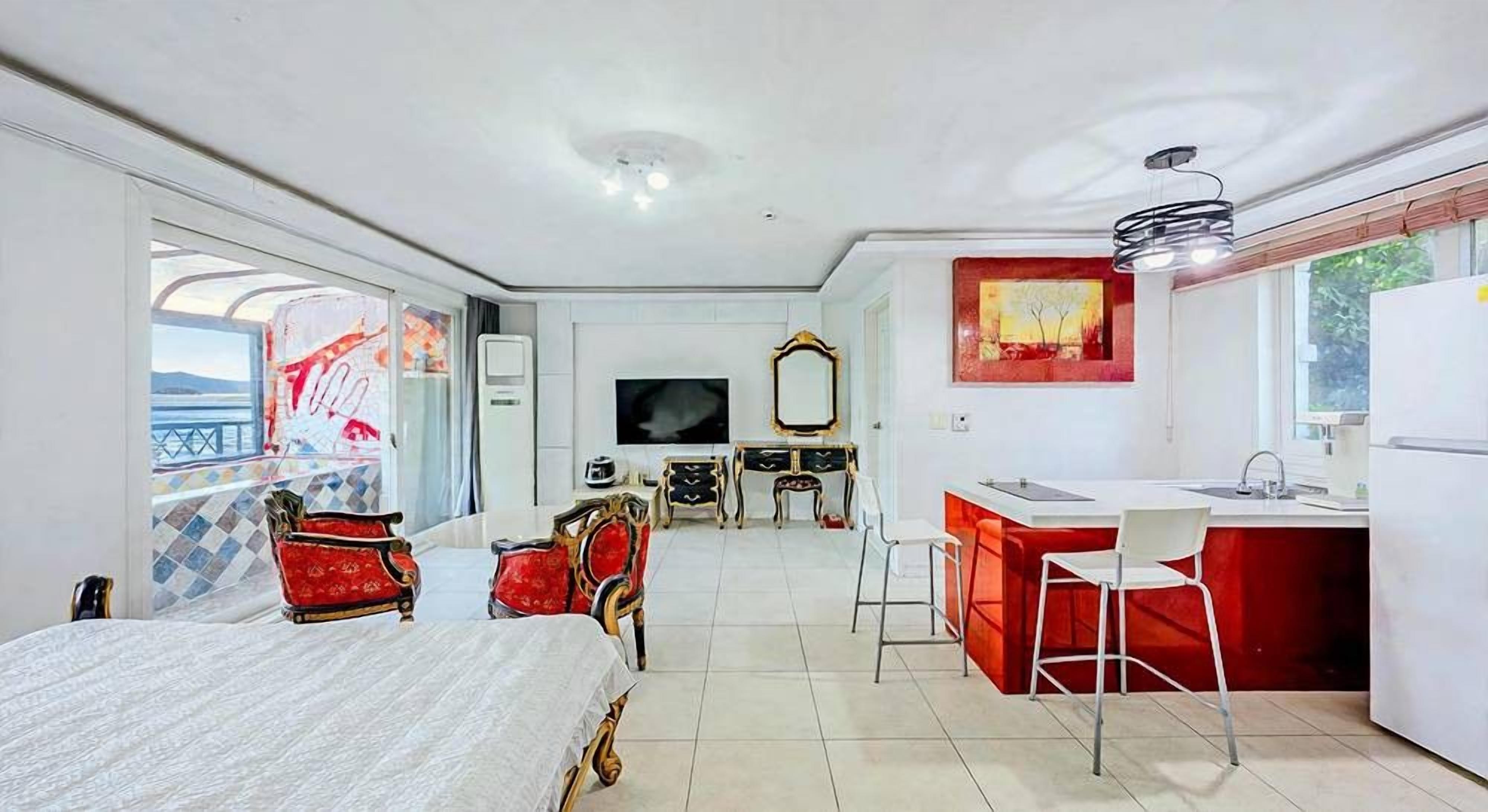 Una habitación con cama, mesa de comedor, sillas, una zona de cocina con lavamanos y un televisor.