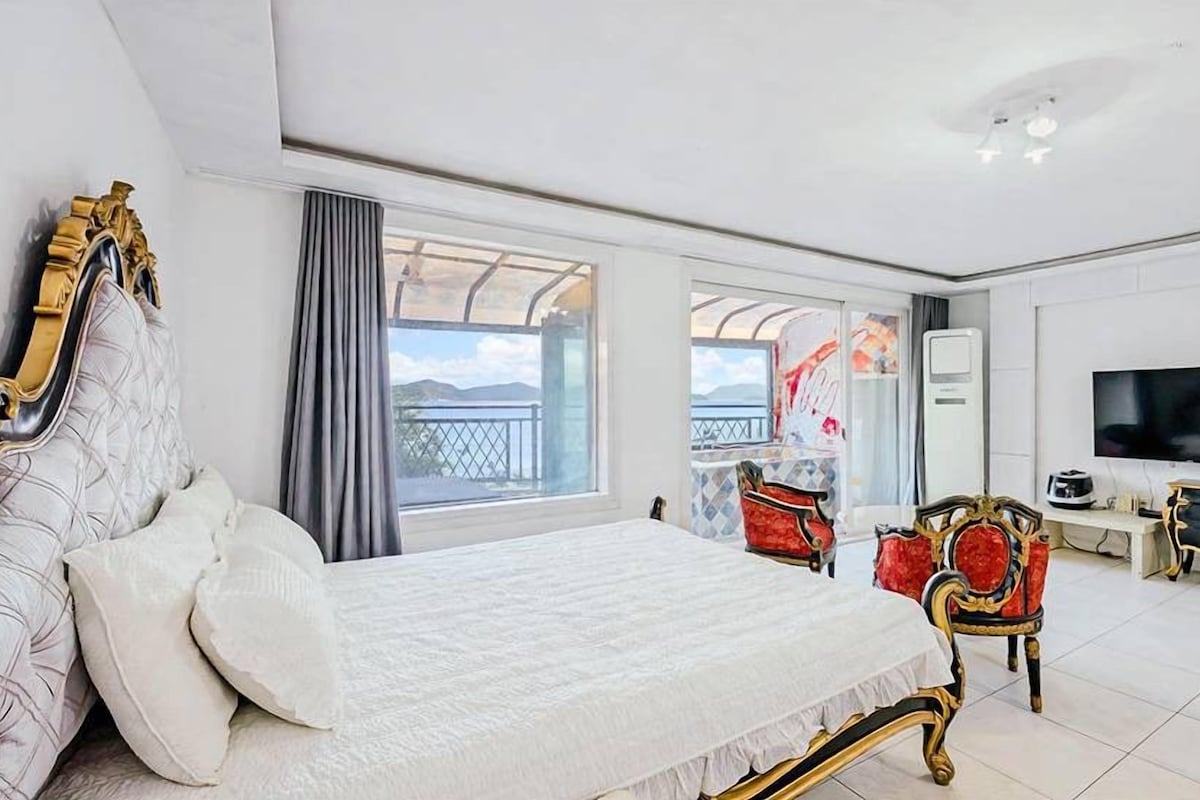 A hotel room with a bed, a television, a desk, and a balcony with a view.