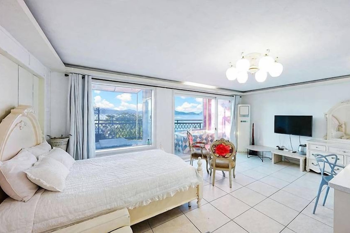 A bedroom with a bed, a TV, a desk, and a chair.