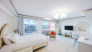 A bedroom with a bed, a TV, a desk, and a chair.