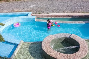 A swimming pool with a unique circular hot tub area and a clear blue water feature.
