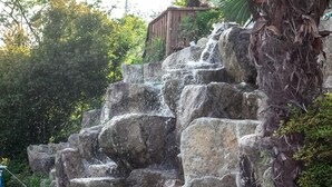 A waterfall cascading over large rocks in a natural setting. - Santamonica Pension (Geoje)