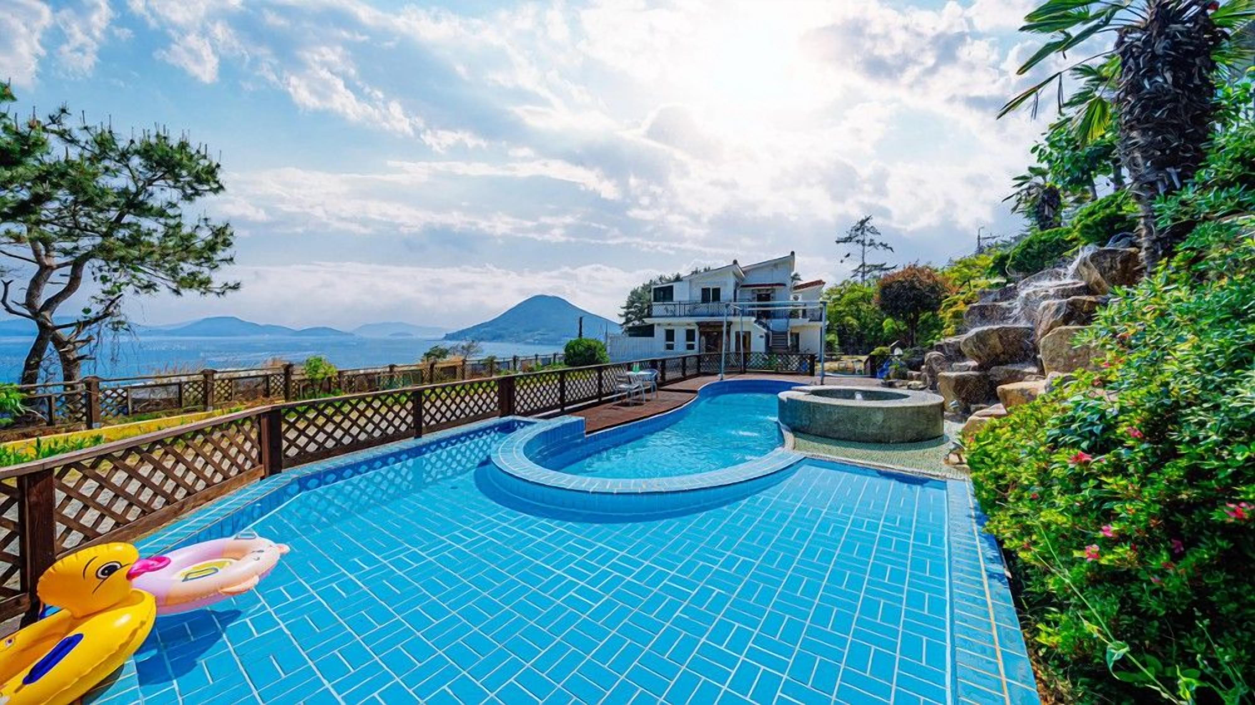 Una piscina con vistas a una montaña y un edificio de dos pisos.