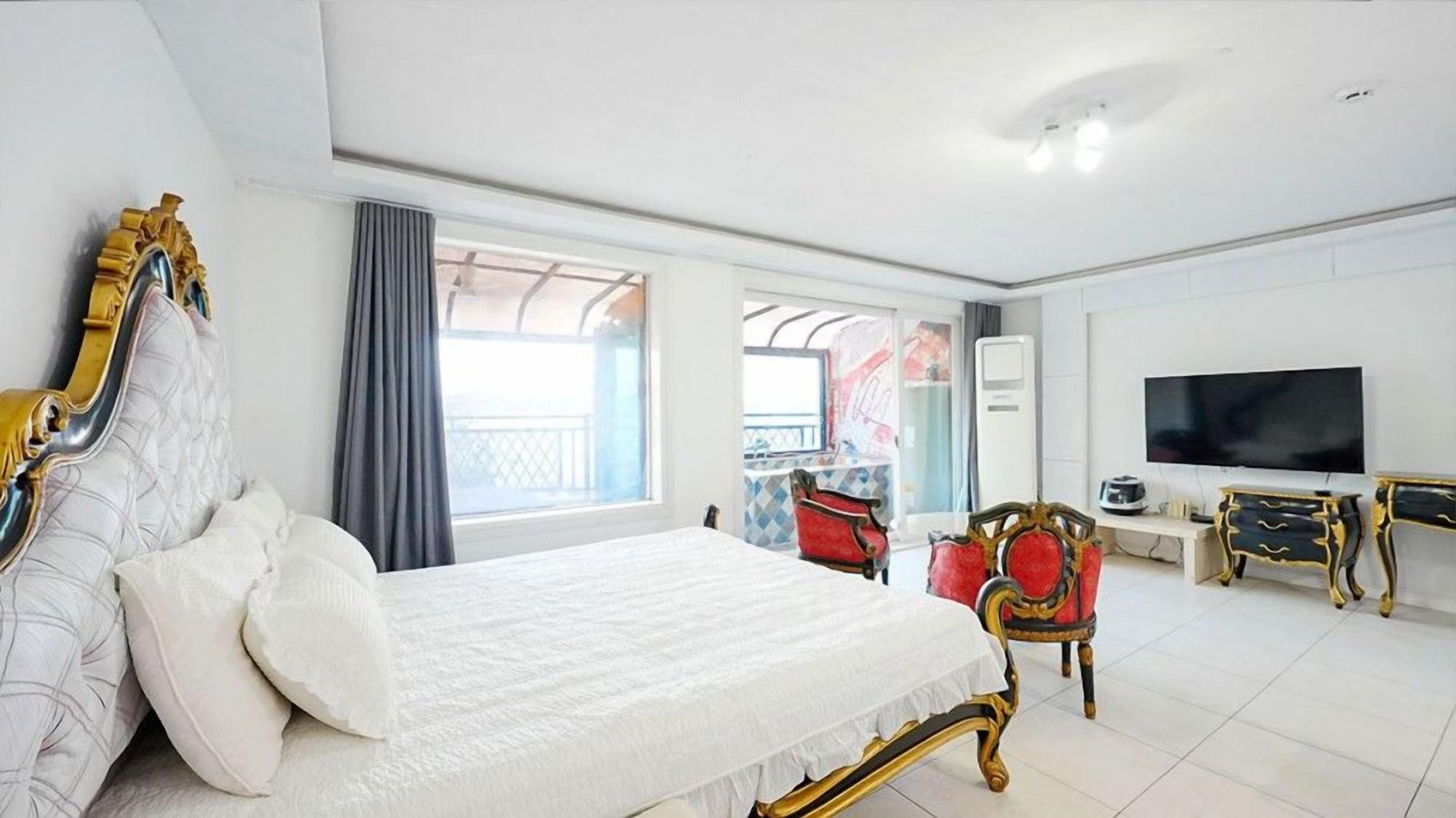 Habitación de hotel con una cama grande, televisión, escritorio y balcón.