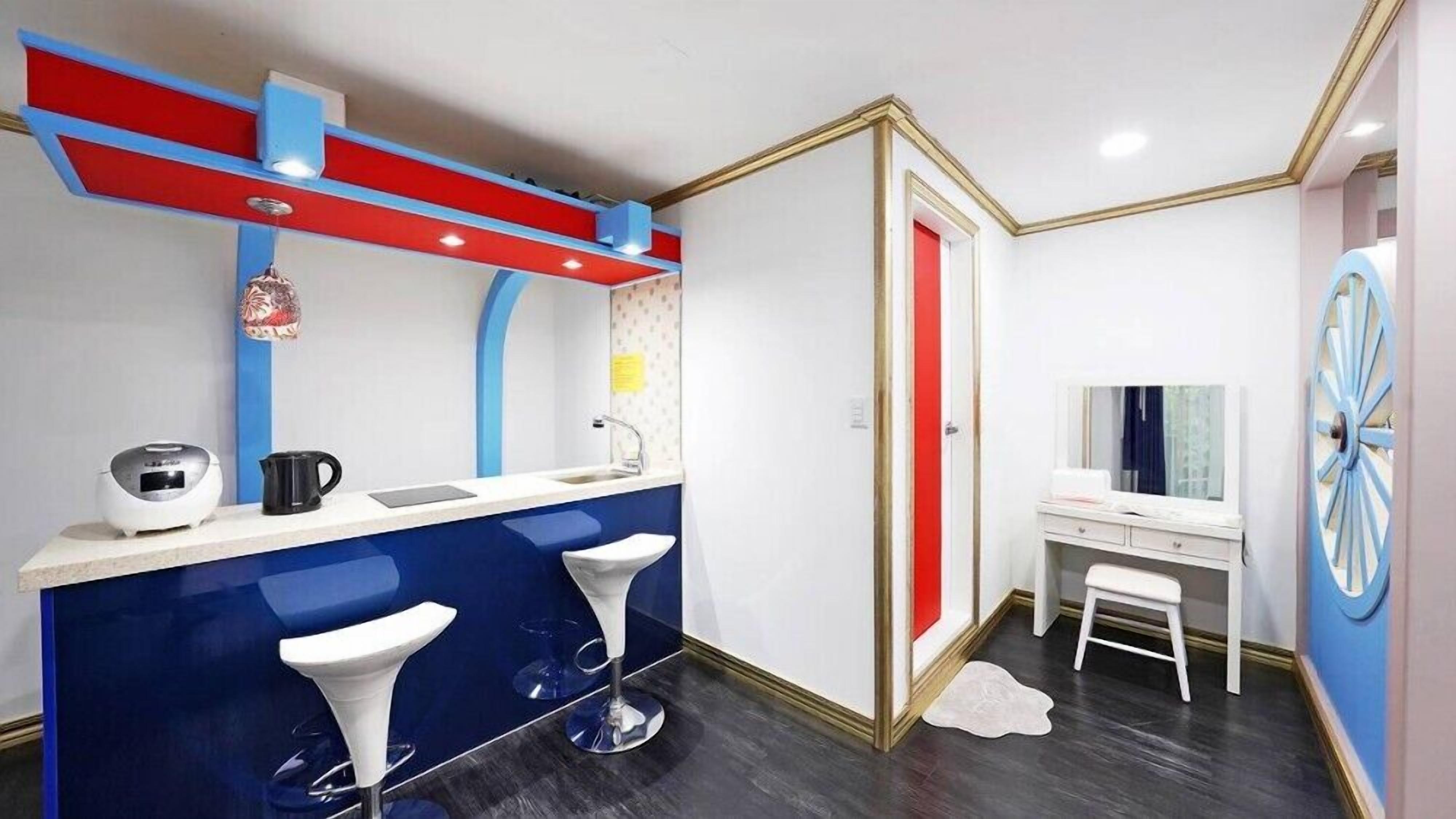 Un baño moderno con tocador azul, lavabo blanco y una pared de acento roja.