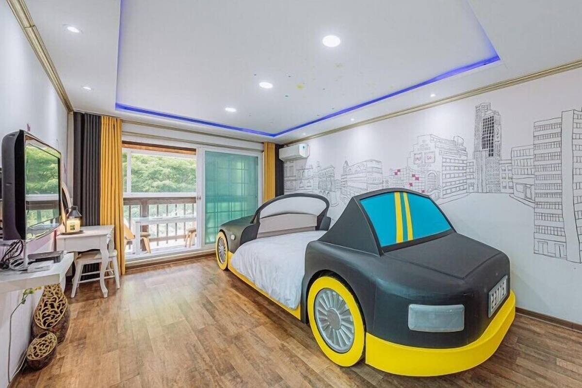 A bedroom with a bed, a desk, a chair, and a wall mural.