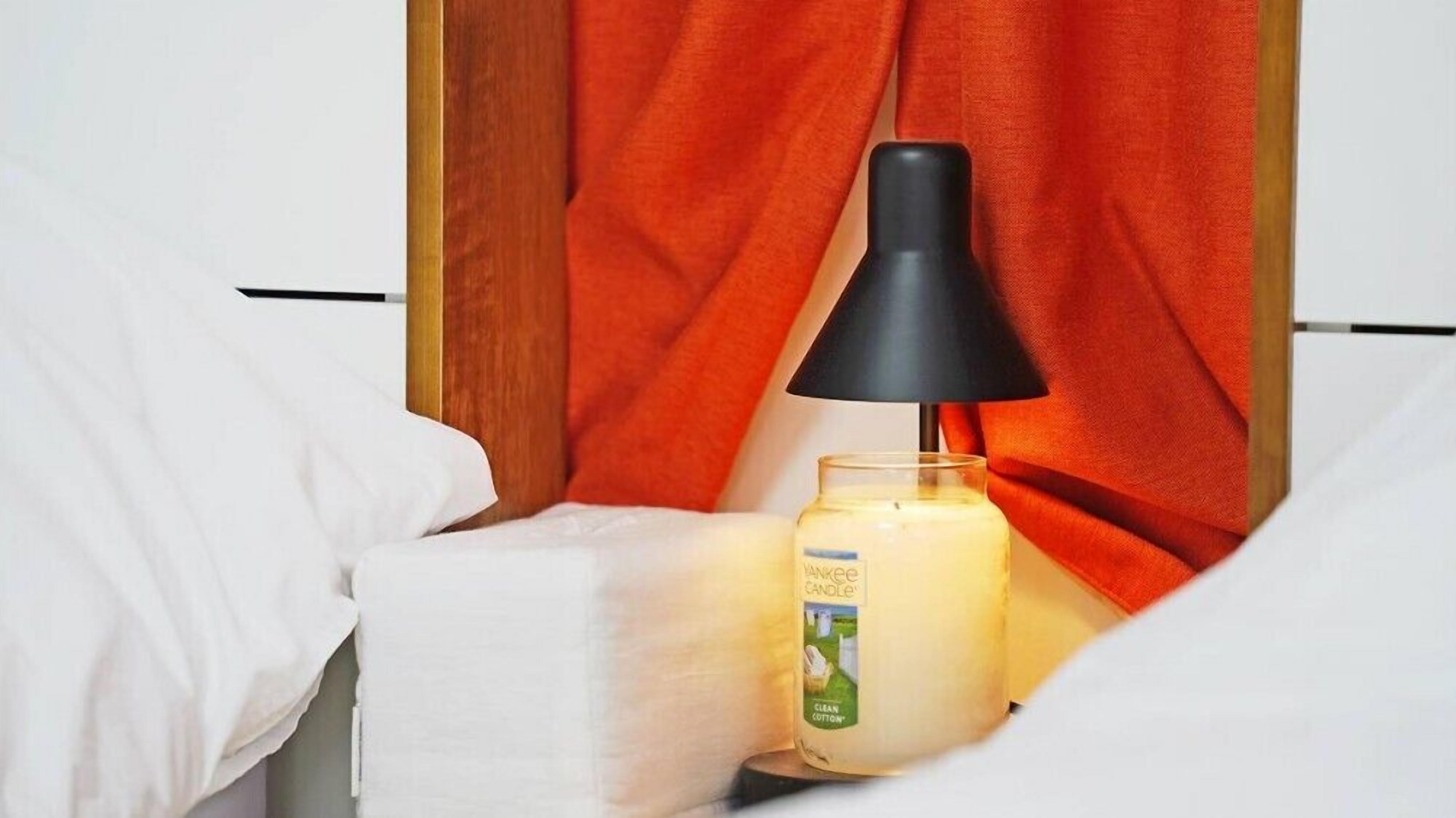 A bedside table with a white candle and a black lamp.