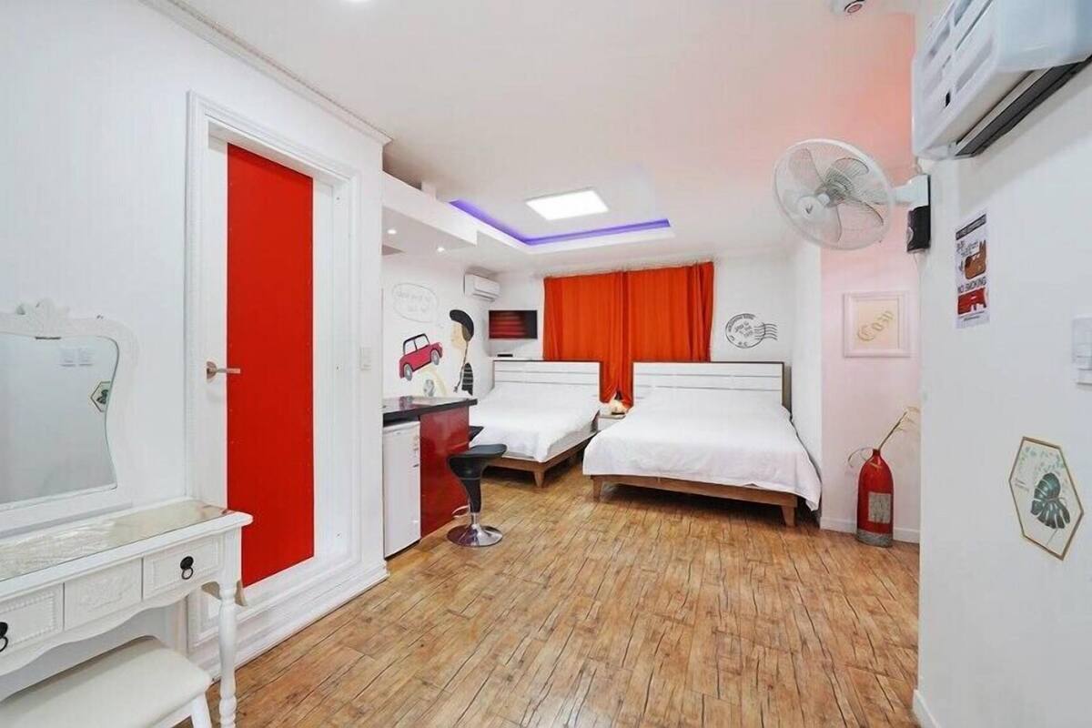 A bedroom with two beds, a desk, a chair, and a mirror.