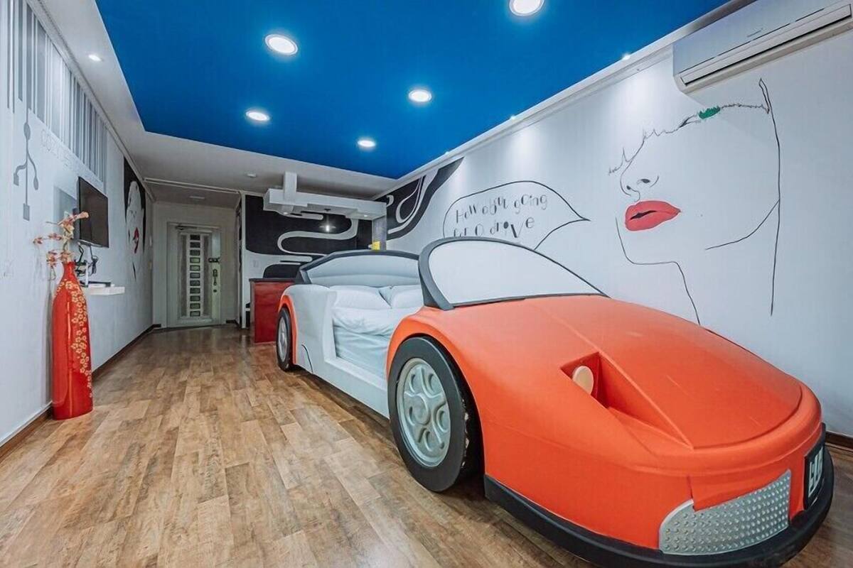 A hallway with a white and orange sports car model, a blue ceiling, and a wall mural.