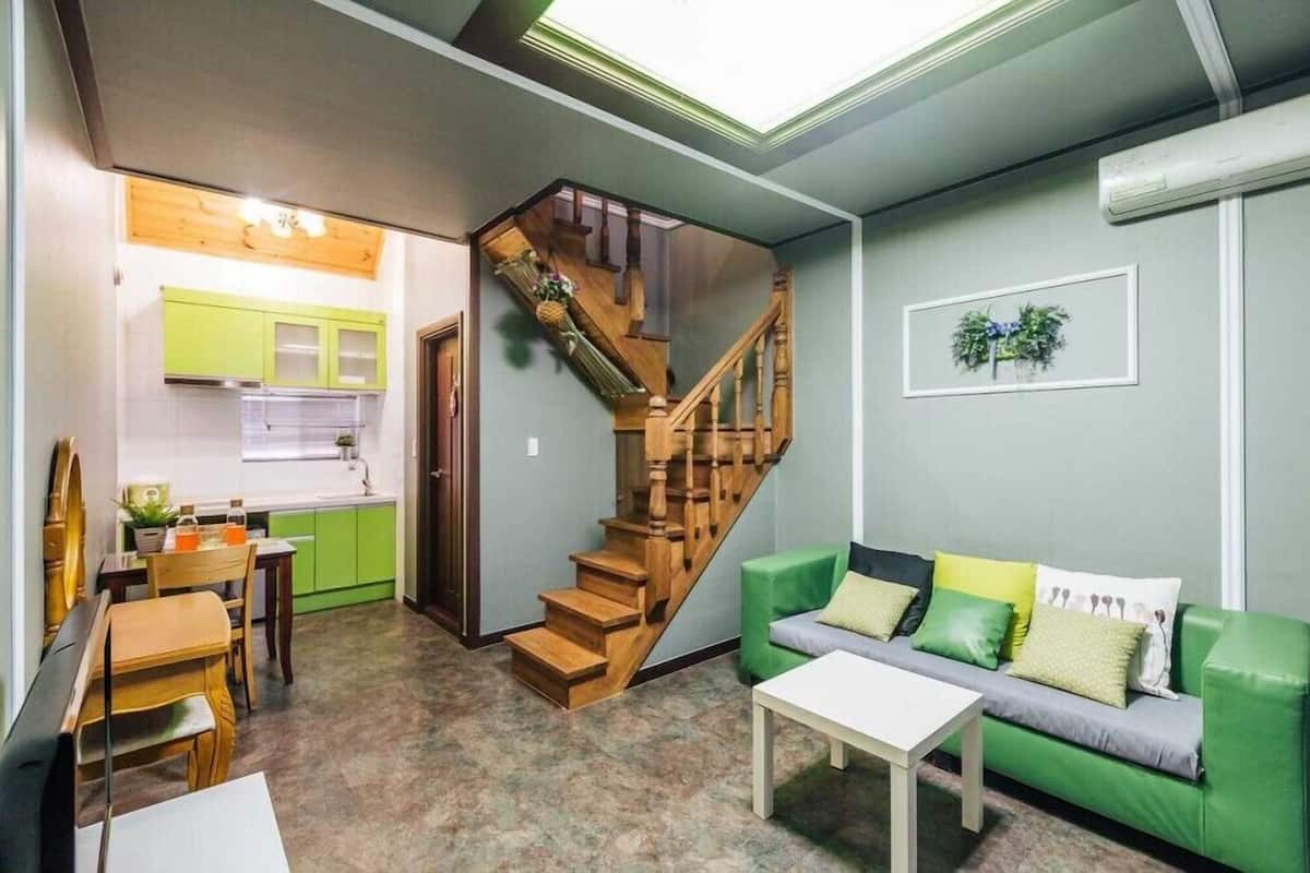 A compact living space with a kitchen, dining area, and a staircase leading to an upper level.