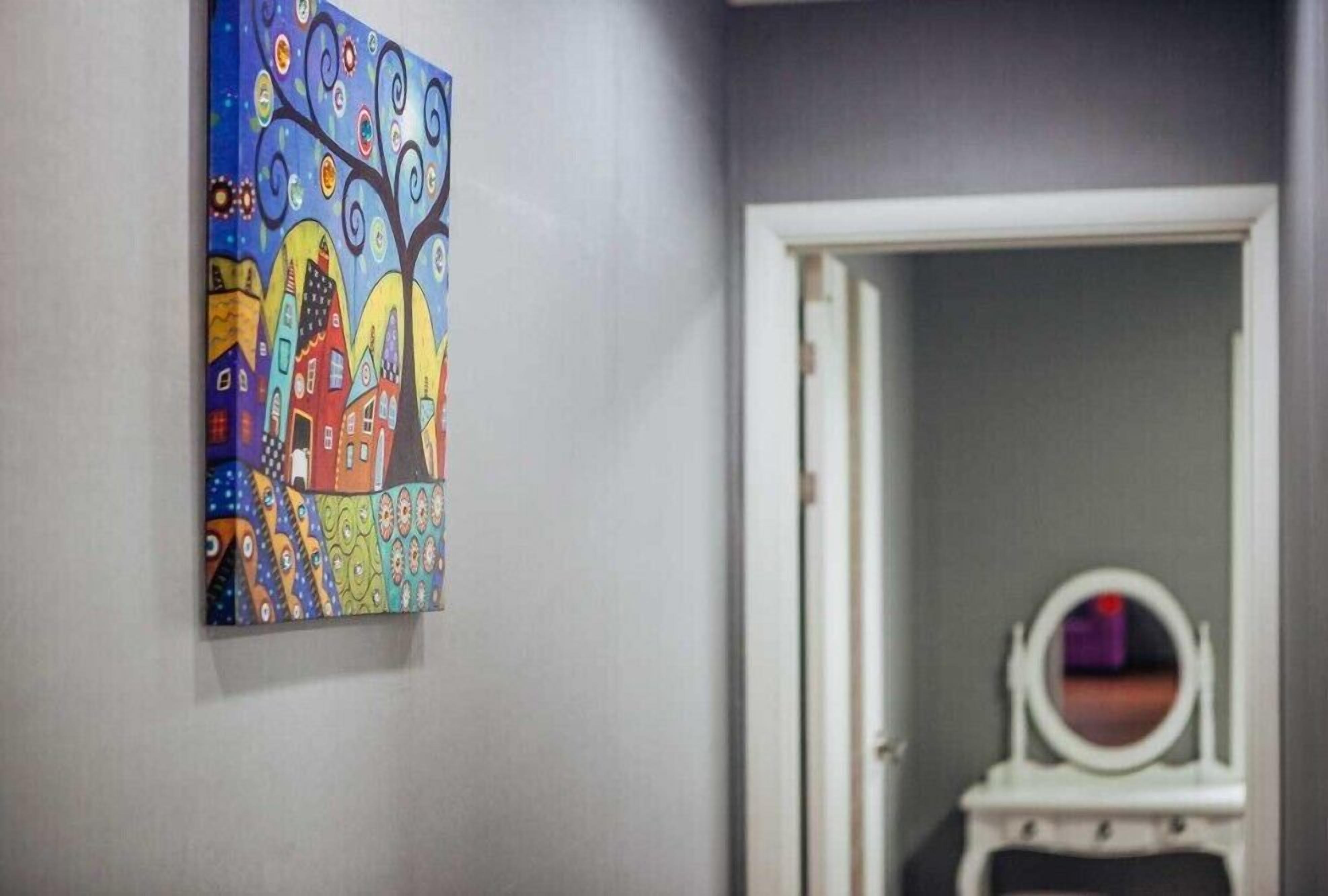 A hallway with a colorful painting on the wall and a door leading to another room.