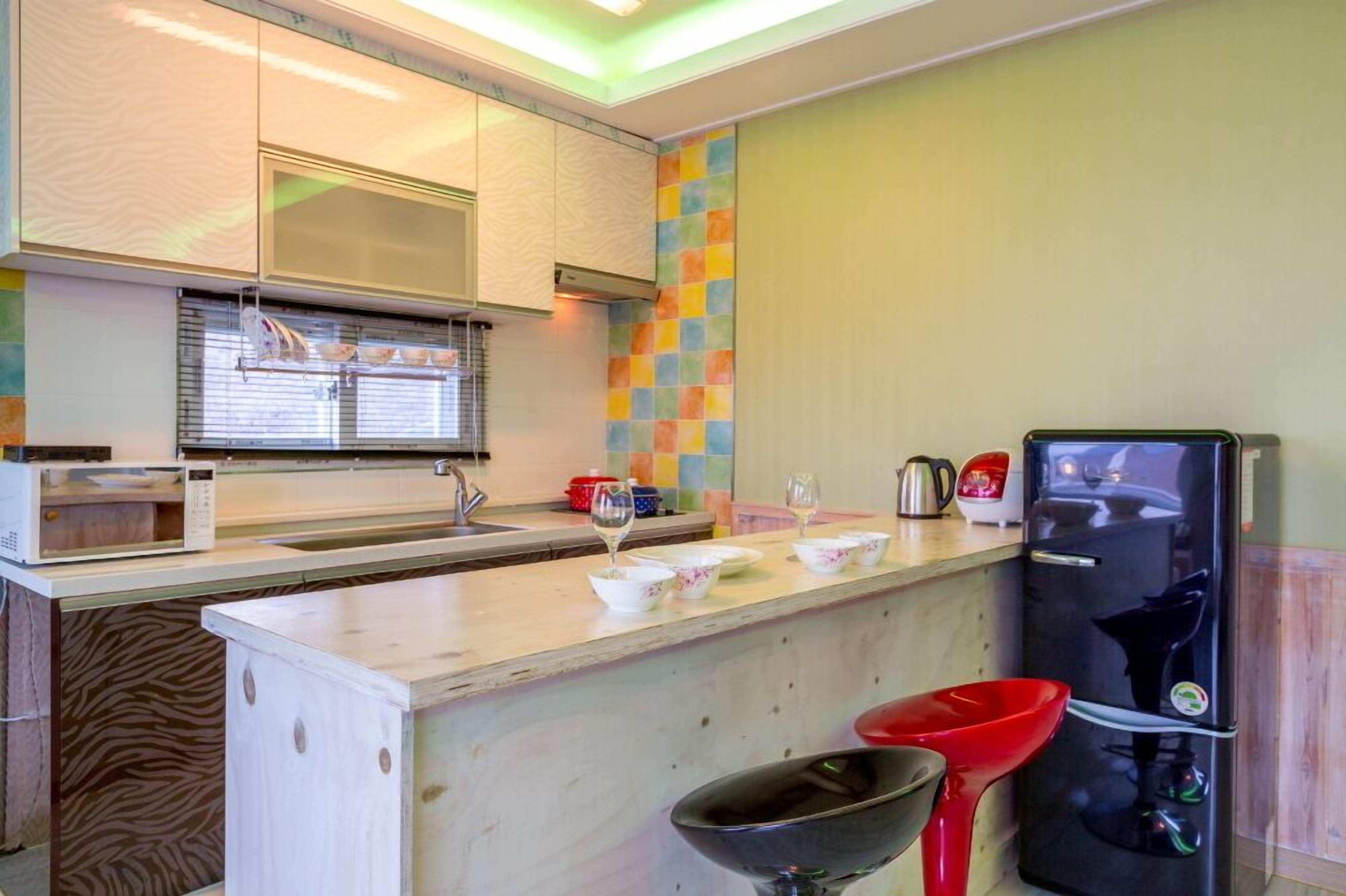 A compact kitchen with a microwave, sink, and a refrigerator.