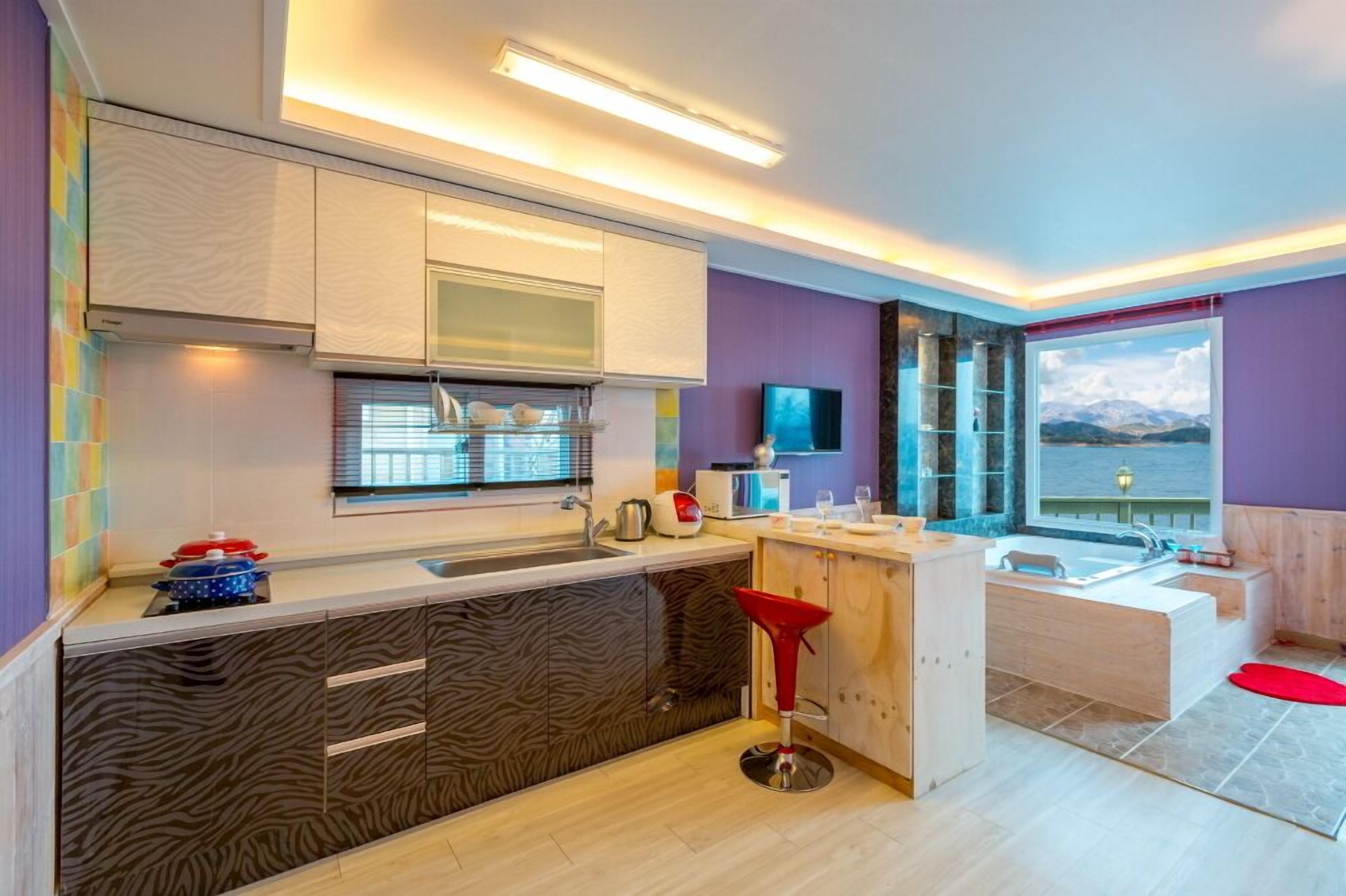 A modern kitchen with a large island, a built-in oven, and a view of the mountains through the window.