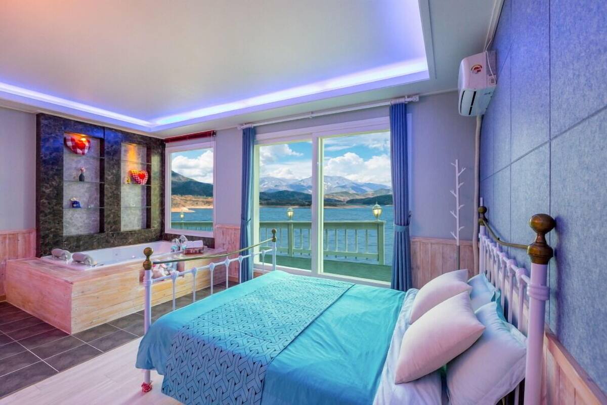 A bedroom with a large bed, a bathtub, and a view of the mountains.